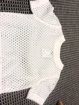 Vit mesh topp från H&M - Säljer en vit mesh topp från H&M med korta ärmar och rund hals. Toppen har ett genombrutet, hålmönstrat tyg som ger en sportig och trendig look. Perfekt att styla lager på lager eller över ett linne.