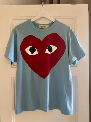 CDG Play t-shirt ljusblå - Size M  - Comme des Garçons PLAY t-shirt i ljusblå med stor heart logo.  Storlek: M Skick: Acceptabelt skick   Populär modell (big heart) som funkar till allt. Nypris ca 1200–1800 kr.  Äkta, made in Japan.  Skriv vid frågor eller för fler bilder