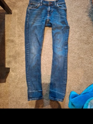 Nudie jeans tight steel terry - Säljer ett par klassiska blå skinny jeans med låg midja och fem fickor. Jeansen har en snygg tvätt och smal passform som sitter tajt längs benen. Perfekta till en avslappnad streetstyle-look. Storlek w26 L28