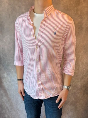 Randig Ralph Lauren Skjorta - Stl M, Slim fit - RIKTIGT FET RL SKJORTA I RANDIGT MÖNSTER MED FÄRGERNA VIT OCH ROSA , perfekt till sommaren som närmar sig! 🏖️🌊 |Mycket bra skick: 9,5/10, utan defekter! | Stl: M |  Modellen är 176cm och väger 75kg,  | Hör av dig vid frågor // Galgen 🫡