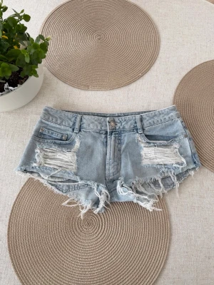 Slitna lågmidjade jeansshorts  - Uppskattad storlek XS. Rakt över midjemått: 37cm. Skickas inom 24h. Se liknande plagg i min profil! 