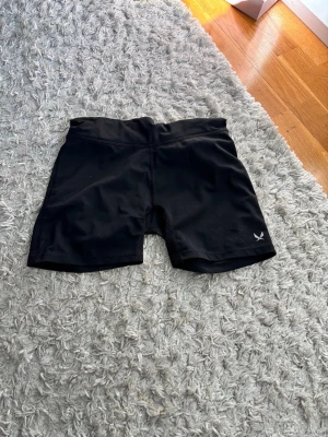 Svarta cykelshorts från soc - Svarta cykelshorts från soc med diskret logga på benet. De har en hög midja och är tillverkade i stretchigt syntetmaterial som passar perfekt för träning. Klassisk och enkel design utan extra detaljer.