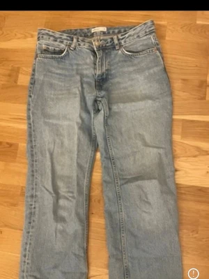 Ljusblå raka jeans - Säljer ett par ljusblå jeans med rak passform och klassisk femficksdesign. Jeansen har normal midja och är tillverkade i ett slitstarkt denimtyg. Perfekta för en avslappnad och trendig look.