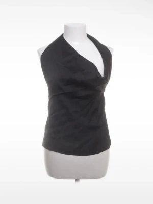 Svart omlott halterneck topp - Snygg svart halterneck topp med omlott-design och knyt i ryggen. Toppen är ärmlös och har en djup v-ringning framtill. Tillverkad i ett glansigt material som ger en lyxig känsla. Perfekt för dig som vill sticka ut med en stilren look.