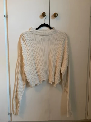 Vit ribbstickad croppad tröja - Säljer en vit ribbstickad tröja med croppad passform och långa ärmar. 