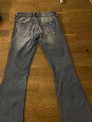 Ljusblå bootcut jeans med broderi - Säljer ett par ljusblå bootcut jeans med snyggt broderade bakfickor. Jeansen har låg midja och klassisk femficksmodell. Tillverkade i mjuk denim med lätt slitning framtill och bak. Perfekta för en avslappnad och trendig look.helt nya men priset går o diskutera
