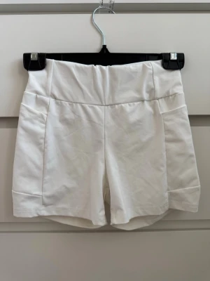 Vita högmidjade shorts - Snygga vita shorts med hög midja och bred linning. De har en enkel och stilren design utan synliga detaljer som knappar eller dragkedja. Perfekta för varma dagar och passar till det mesta. Gjorda i ett mjukt och bekvämt material. Använde de en gång, under studentklänningen ☺️💗