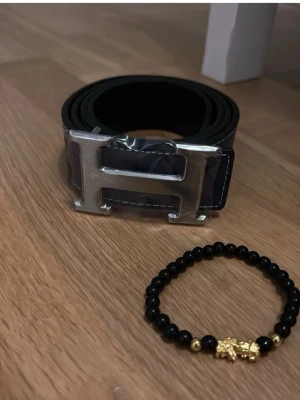 Mörkblå bälte med stor H-spänne - Snyggt mörkblå bälte med ett stort, blankt H-format spänne i silverfärg. Pris kan diskuteras vid snabb affär. 125cm