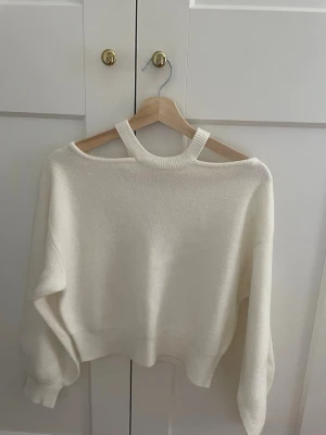 Vit stickad tröja med cut out-hals - Trendig vit stickad tröja med unik cut out-detalj vid halsen. (Kan skickas direkt)