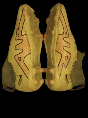Gula Nike fotbollsskor med socka - Säljer ett par gula Nike fotbollsskor med svart swoosh och integrerad socka för extra stöd runt ankeln. Skorna har en slimmad design, mönstrad sula för bra grepp och elastisk plös. Perfekta för dig som vill sticka ut på planen.
