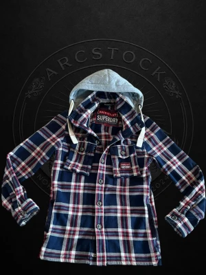 overshirt från superdry - Snygg overshirt från Superdry i blått, rött och vitt rutmönster. Skjortan har två bröstfickor med knappar och en grå huva med vita snören. Perfekt lager-på-lager-plagg med cool streetkänsla.