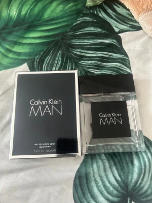 Calvin Klein MAN Eau de Toilette 100ml - Calvin Klein MAN Eau de Toilette 100ml med stilren, fyrkantig glasflaska och svart etikett. Doften är maskulin och modern, perfekt för dig som gillar klassiska och fräscha parfymer. Levereras med originalförpackning.den har runt 90-70 ml kvar