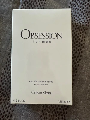 Obsession for Men parfym 125 ml - Obsession for Men från Calvin Klein är en eau de toilette. Flaskan innehåller 125 ml och doften har inslag av kryddor och trä. Perfekt för dig som gillar klassiska och maskulina parfymer. Helt ny och aldrig använd, paletet är bara öppnad för att ta bilder. Skriv vid funderingar.