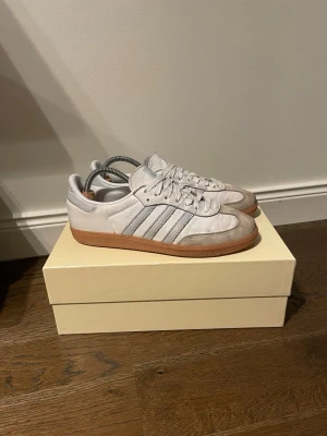 Adidas Samba OG - Klassiska Adidas Samba OG sneakers i vitt med ljusgrå detaljer. Lite smutsiga på mockan men går att fräscha upp med en borste annars riktigt fint skick!