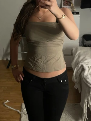 Beige tubtopp med slits  - Säljer en beige tubtopp i mjukt bomullsmaterial. Toppen är croppad och axelbandslös med en enkel och stilren design. Perfekt att matcha med jeans eller kjol för en trendig look.
