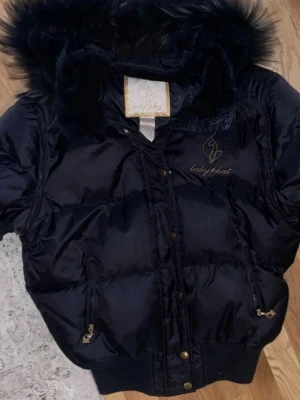 Y2K vintage baby phat jacka - Jätte snygg vintage baby phat jacka, jag köpte den på Plick för tre år sedan men har aldrig använt den. Den är i bra skick förutom ett ihop sytt hål på insidan av jackan (se på bild 6) men det syns inte när man har på sig den. Det finns också en liten röd fläck på insidan av jackan. Den är storlek 4XL men den passar fint som en baggy jacka på er som har storlek s/m. Det finns dragkedjor på ärmarna och jackan har guldiga katt detaljer. Har katt hemma.   Jackan ligger också uppe på min vinted💗💞
