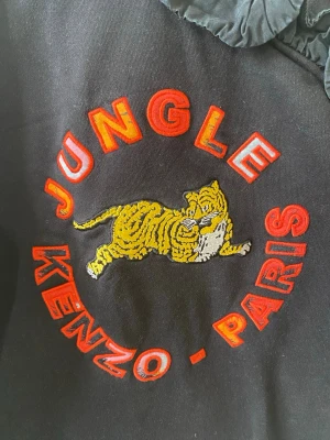 Svart Kenzo Jungle sweatshirt - Cool svart sweatshirt från Kenzo med broderad tiger och texten 'Jungle Kenzo paris” framtill. Knappt använd, superbra skick!! Storlek M! Skriv vid frågor, fler bilder eller testa skicka prisförslag! 💕