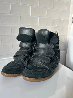 Isabel marant liknande svarta wedgeskor - •Supersnygga svarta kilklack/wedge sneakers som ar liknande till de virala Isabel marant bekett skorna. • Säljer för att de är för stora • Köpta second hand • storlek 37 • står att det är äkta läder • märke blue haven Skriv om ni har fragor! 
