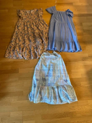 Tre somriga klänningar i blå toner - Tre klänningar i olika blå nyanser. En blommig kortärmad klänning med volang, en ljusblå kortärmad klänning med volang och en ärmlös ljusblå klänning med volangkant. Perfekta för varma dagar och har en luftig passform.     Klänningarna är från tre olika märken men den bruna med blommor är från SHEIN. Det är 30 kr styck och de är lite olika i längden