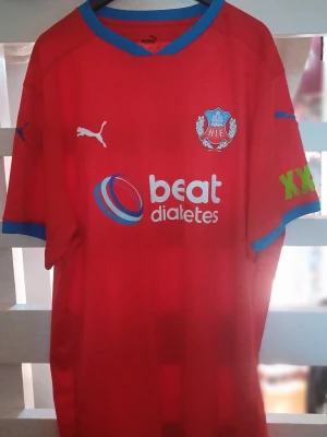 Röd HIF matchtröja från Puma - Röd Helsingborgs IF matchtröja från Puma med blå detaljer vid krage och ärmslut. Tryck med klubbmärke, Puma-logga, sponsorloggor och texten 'Skånes Stolthet' i nacken.  Storlek L . Har aldrig använt tröjan den är ny skick.