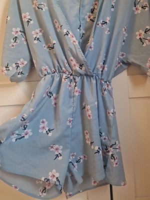 Jumpsuit - Blå jumpsuit men vita och lila blommor