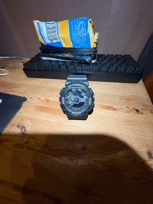 Svart G-Shock klocka digital/analog - Cool svart G-Shock klocka med både digital och analog display. Klockan har robust design, tydliga knappar och tåligt syntetarmband. Perfekt för dig som gillar sportig och tuff stil. G-Shock-loggan syns tydligt på framsidan.