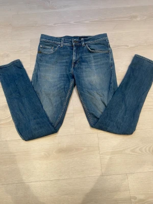 Blå jeans från T/J med raka ben - Säljer ett par klassiska blå jeans från Tiger of Sweden med raka ben och femficksmodell. Jeansen har snygga slitningar och kontrastsömmar samt en läderpatch med logga bak i midjan. Perfekta till en avslappnad stil och passar till det mesta.
