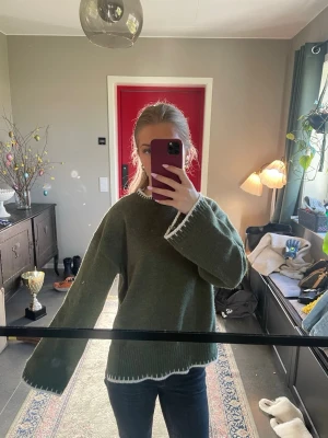 Grön oversized stickad tröja - Mysig grön stickad tröja med oversized passform och vita detaljer vid ärmslut, halsringning och nederkant. Har även en slitt nere på båda sidorna. Skriv om ni har frågor💕