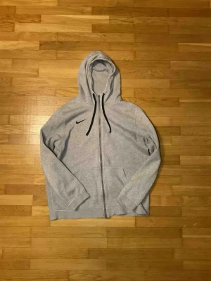 Nike kofta - Säljer min använda Nike zip då jag inte använder den längre. Det finns 2 skador på den vilker är i slutet på ärmarna på både ärmarna se på bild 3 och 4