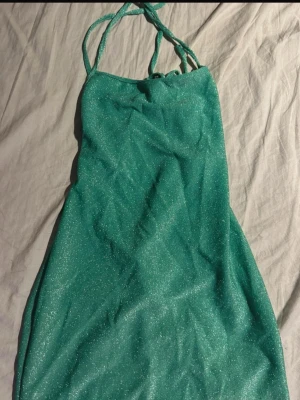 Glittrig grön festklänning - Grön kort klänning med glittrigt material som verkligen sticker ut. Tunna band och öppen rygg med snygga snörningsdetaljer som ger en extra wow-effekt Perfekt för fest, utekväll eller när du vill vara kvällens blickfång ✨💚(ifrån shein) 