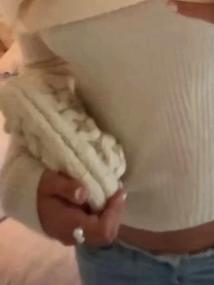 Beige stickad cluch väska - Säljer en beige stickad handväska med chunky flätmönster. Väskan har en mjuk och klumpig form, perfekt att bära i handen. Materialet är grovt stickat och ger en trendig look. Passar dig som gillar unika accessoarer och stickade detaljer.