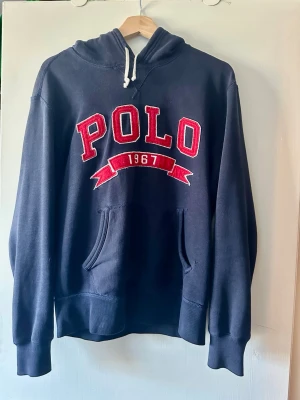 Marinblå hoodie från Polo Ralph Lauren - Säljer en riktigt skön polo Ralph Lauren hoodie! | Mycket fint skick finns något mindre tecken på användning man inte märker av! | Storlek S. | Ställ gärna frågor innan du köper!