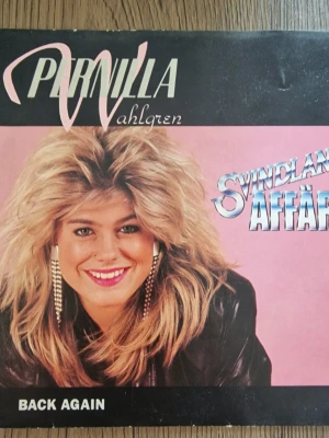 Pernilla Wahlgren singel Svindlande affärer / Back again vinyl - Pernilla Wahlgren singel Svindlande affärer / Back again på vinyl. Skivan är ett 7-tumsformat med låten Svindlande affärer på ena sidan och Back again på den andra. Omslaget visar artistfoto på framsidan och låtlista med krediter på baksidan. Utgiven av skivbolaget som anges på omslaget, med tryckår enligt märkning på baksidan.