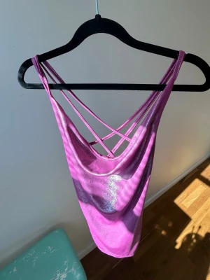 Glittrig lila linnetopp med smala band - Säljer en glittrig lila linnetopp med tunna axelband och snyggt korsade band i ryggen. Toppen har en draperad, lite lös passform och är perfekt för dig som vill sticka ut 🪩💗