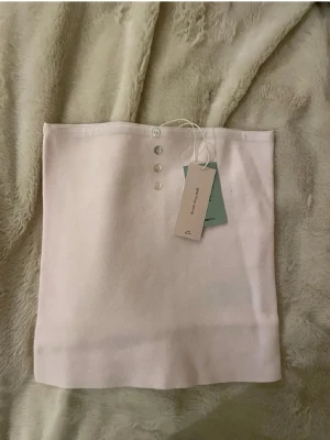 Ljusrosa tubtopp från Gina Tricot - Supersöt ljusrosa tubtopp från Gina Tricot med fyra små knappar framtill. Toppen är axelbandslös och har en enkel, clean look.