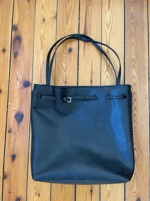 Väska H&M - Superfin svart väska i fuskläder🩷 Har mindre defekt annars hel😊