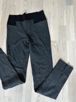 Mörkgrå mjukisbyxor med bred midja - Mörkgrå mjukisbyxor med bred svart resår i midjan och raka ben. Byxorna har en enkel design utan synliga loggor och är tillverkade i ett mjukt, stretchigt material som känns skönt mot huden. Perfekta för chill dagar eller när du vill vara bekväm. Rök och djurfritt hem. Pruta gärna !🌸