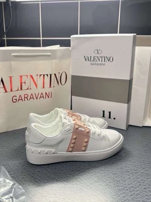 Valentino Rockstud vita sneakers - Snygga vita sneakers från Valentino Garavani med ljusrosa band och ikoniska nitar över vristen.  Storlek 37-39 finns