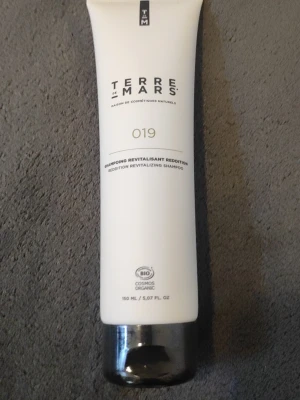 Terre de Mars revitaliserande schampo - Säljer ett Terre de Mars 019 Bédition Revitalizing Shampoo i vit tub med silverfärgat lock. Schampot är ekologiskt certifierat och innehåller 150 ml. Tuben har en stilren design och är perfekt för dig som vill ha naturlig hårvård.
