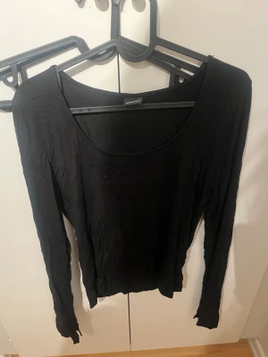 Svart långärmad topp Gina Tricot - En enkel svart långärmad topp från Gina Tricot med rund halsringning. Toppen har en slim passform och är tillverkad i mjukt material som passar perfekt till alla outfits. Stilren och lätt att matcha.