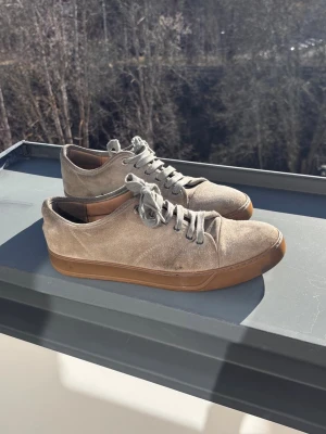 Gråa sneakers i mocka från Lanvin - Riktigt feta skor från Lanvin i mjuk mocka i storlek 9, vilket är 43 ungefär. Klassisk låg modell med metallöljett med Lanvin-logga. Sko sulen är inte jätte bra skick men går att byta ut. Annars riktigt snygga skor nu till sommarn🌸