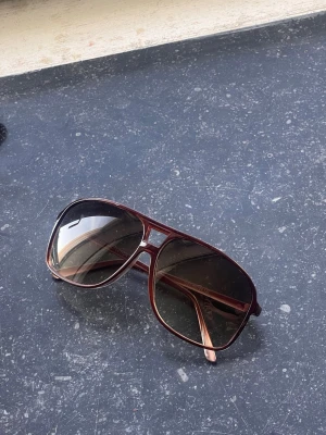 Bruna aviator solglasögon - Snygga aviator solglasögon med bruna bågar och tonade linser. Klassisk form som ger en cool vibe och passar perfekt till soliga dagar. Ramen är i plast och har en lätt metall-look. Köpta i Kalifornien, USA, använda en dag. Inget synligt märke på bågarna.