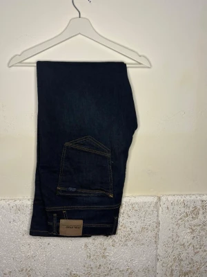 Mörkblå jeans från BLEND - Snygga mörkblå jeans från BLEND med klassisk femficksdesign och kontrastsömmar. Jeansen har en rak passform och är tillverkade i ett slitstarkt denimtyg. Perfekta för en avslappnad och trendig look.