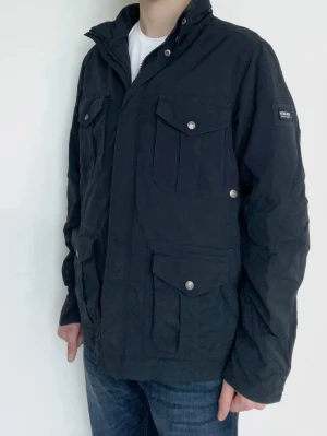 Woolrich Fieldjacket  - Väldigt eftraktad Woolrich jacka i färgen marinblå! Fint skick, inga defekter. Storlek L, modellen är ca 182. Kontakta mig för fler frågor och funderingar! Perfekta vårjackan!
