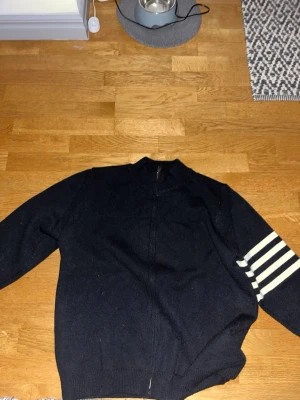 Svart stickad tröja med vita ränder från thom browne - En svart stickad tröja från one browne säljs pågrund av för stor.
