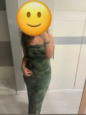Axelbandslös långklänning camouflage - Grön axelbandslös långklänning med camouflage-mönster och tight passform. Klänningen har en rak överdel och är figurnära hela vägen ner. Materialet känns stretchigt och bekvämt, perfekt för dig som gillar en edgy stil.