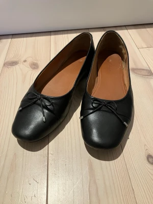Svarta ballerinaskor Vagabond i skinn storlek 37 - Klassiska svarta ballerinaskor i skinn med en liten rosettdetalj framtill. Storlek 37 innermått 24 cm. I mycket bra skick.
