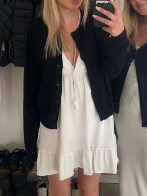 Vit volangklänning med v-ringning - Säljer en väldigt enkel men söt vit klänning med volangkant nedtill och djup v-ringning. Klänningen är även korsad i ryggen. Inga fläckar eller tecken på användning. Skriv för fler bilder💕