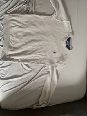 Ljusgrå tröja Polo Ralph Lauren - Snygg ljusgrå stickad tröja från Polo Ralph Lauren med klassisk mörkblå logga broderad på bröstet. Tröjan har rund halsringning och långa ärmar. Perfekt för lager på lager och enkel att matcha med jeans eller kjol.