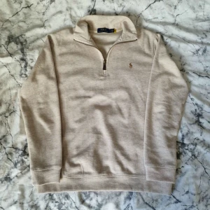 Ralph Lauren half zip | Beige - Klassisk Ralph Lauren half zip med tunnare material, perfekt nu när sommaren är runt hörnet. Är som ny då den endast är testad. Färgen är beige med lite mörka toner här och där. Måtten på sista sidan: A:53cm B:65cm C:62cm D:44cm